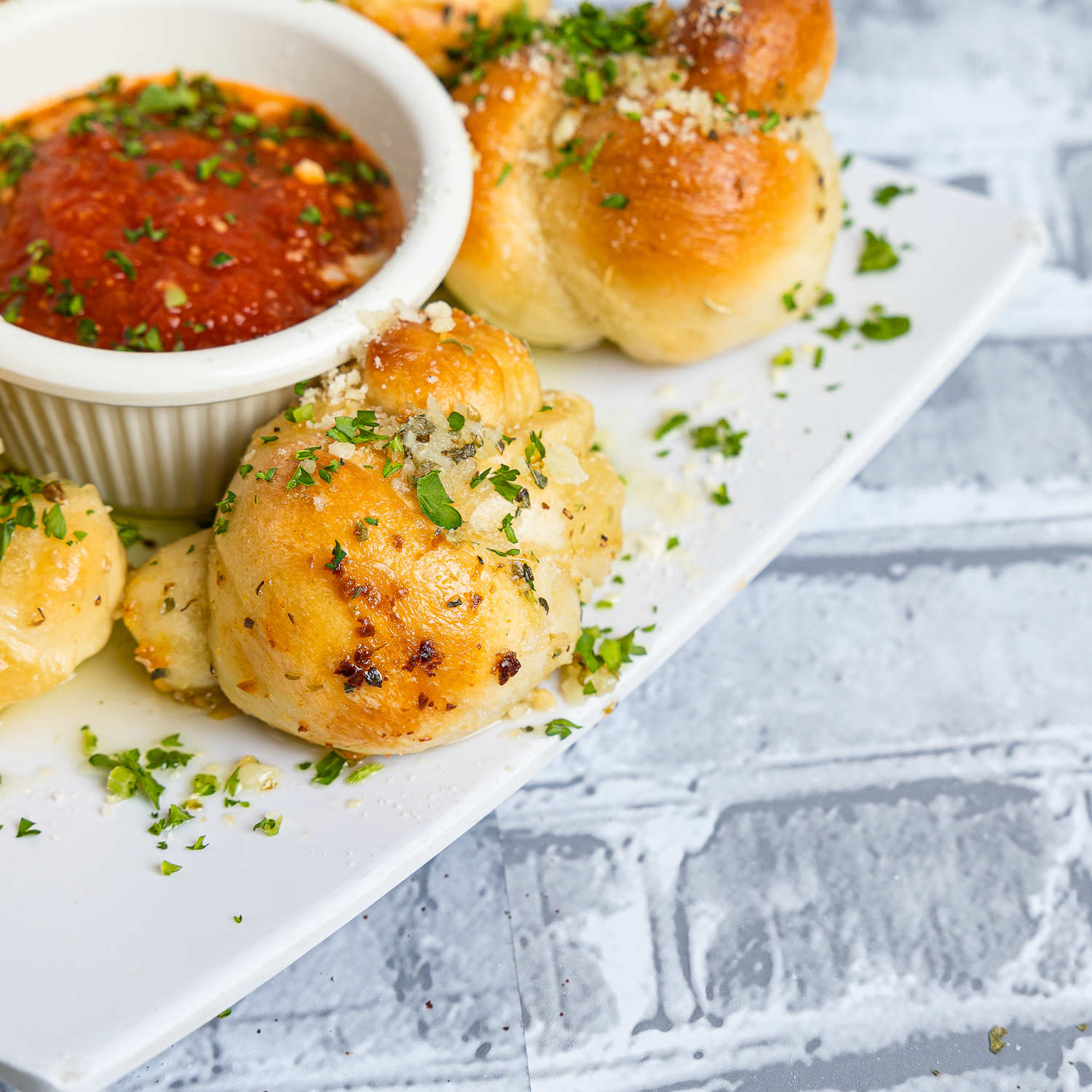 Garlic knots appetizer with marinara sauce on a white plate.